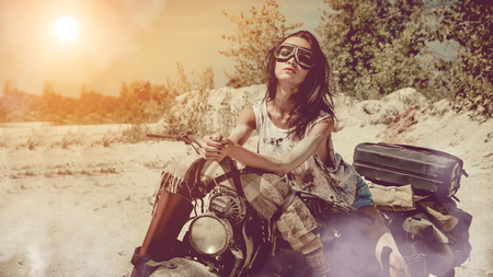 Sexy biker woman on the desert background. Artistic toning.の写真素材