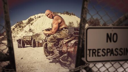 Muscular bald biker on the desert background.