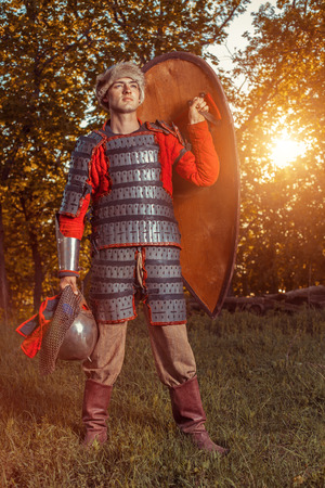 Brave slavic warrior with shield on the summer forest background.
