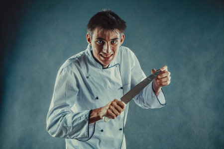 Evil waiter with wolf eyes is holding the knife.の写真素材