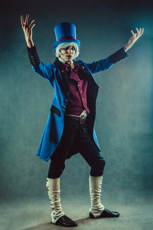 Smiling circus actor in blue tuxedo is presenting something.の写真素材