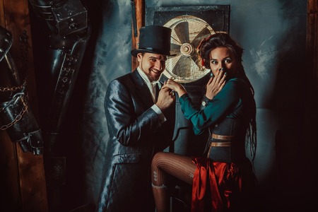 Pretty flirting couple dressed in vintage costumes on the dark room background.の写真素材