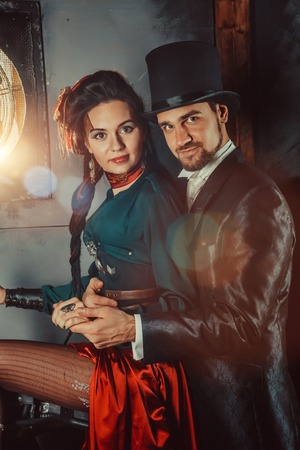 Pretty flirting couple dressed in vintage costumes on the dark room background.の写真素材