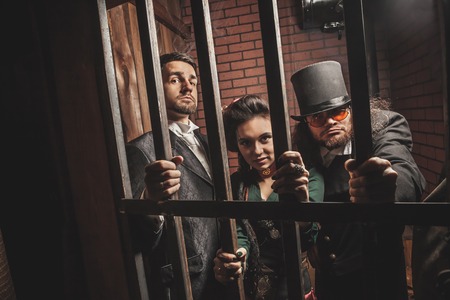 Two gentlemen and a lady behind bars in the prison.の写真素材