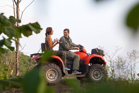 Man and woman are discussing their trip while sitting on a quadbike.の写真素材