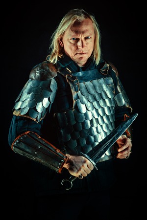Powerful blond knight with the sword on the dark background