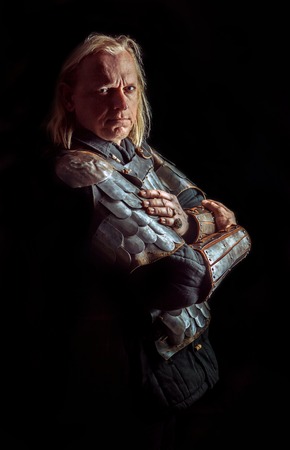 Powerful blond knight is standing with the crossed arms on the dark backgroundの写真素材