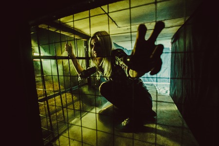 Frightened blond woman in the dark cage.の写真素材