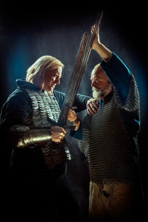 Medieval knights are fighting on swords. Dark background.の写真素材