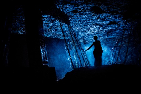 Silhouette of a mysterious witch on the suspension bridge with clouds of smoke around her.の写真素材