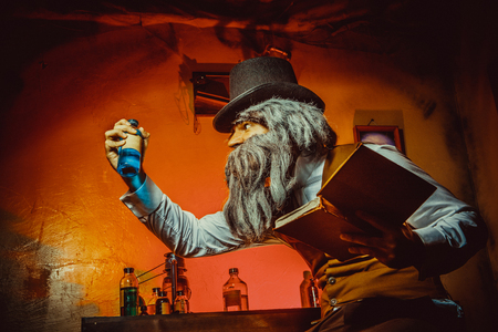 Bearded man with the book in one hand and bottle in anotherの写真素材
