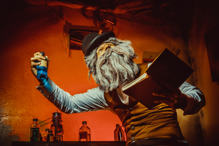 Bearded man with the book in one hand and bottle in anotherの写真素材