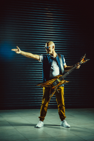 Bold guitarist making a rock and roll gesture while screaming and playingの写真素材