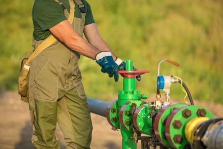 Oil worker is turning valve on the oil pipeline.の写真素材