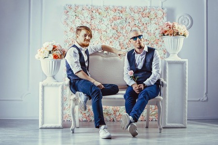 Two hipsters are sitting on the sofa and waiting for their girlfriendsの写真素材