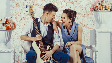 Young couple is sitting on the sofa with the electric guitar.の写真素材