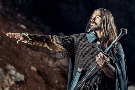 Long haired knight with the two-handed sword. Rocks on the background.の写真素材