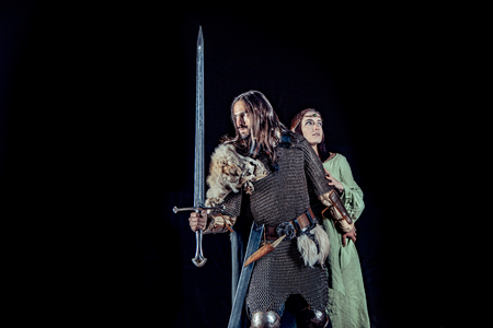 Medieval knight with his beloved lady. Dark forest on the background.