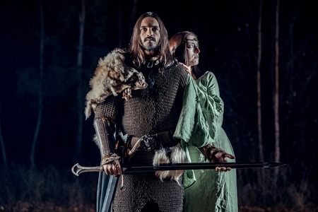 Medieval knight with his beloved lady. Dark forest on the background.の写真素材