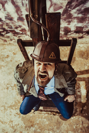 Man is acting as a prisoner sitting in the electric chair.の写真素材