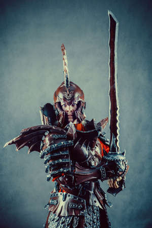 Portrait of a medieval female knight in armor with sword over grey background.の写真素材