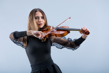 Violinist woman in the evening gown on the grey background.の写真素材