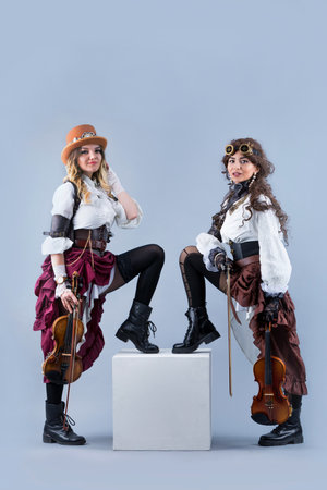 Country girls with violins. Women with violins on the grey background. Women in western style with violas. Cowgirls playing violins country music.の写真素材