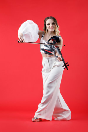 Violinist woman in the stage costume on the red background.の写真素材