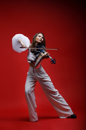 Violinist woman in the stage costume on the red background.の写真素材