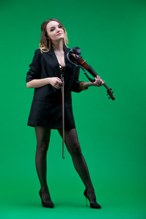 Violinist woman in the black blazer on the green background.の写真素材