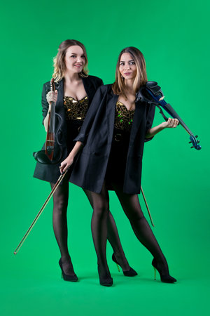 Violinist women duet in the black blazers on the green background.の写真素材