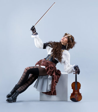 Country girl with violin. Woman with violin on grey background. Woman in western style with violin. Cowgirl playing the violin country music.の写真素材