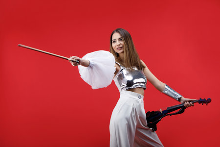 Violinist woman in the stage costume on the red background.