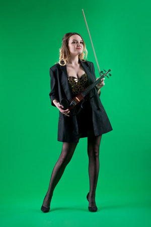 Violinist woman in the black blazer on the green background.の写真素材