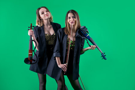 Violinist women duet in the black blazers on the green background.の写真素材