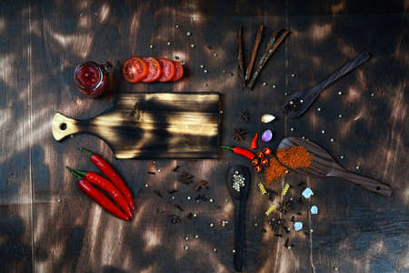 red chili and tomato, salt, garlic, rosemary on a dark wooden background; ingredients for cooking; cover cookbook; asian cuisine, free space for textの写真素材