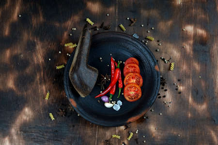 red chili and tomato, salt, garlic, rosemary on a dark wooden background; ingredients for cooking; cover cookbook; asian cuisine, free space for textの写真素材