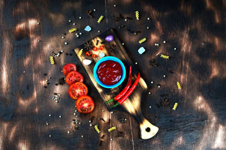 red chili and tomato, salt, garlic, rosemary on a dark wooden background; ingredients for cooking; cover cookbook; asian cuisine, free space for textの写真素材