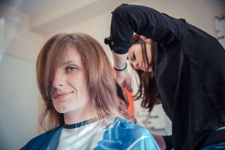 Hairdresser cutting client's hair in beauty salon. 2016