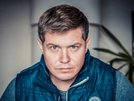 Portrait of a handsome young man standing inside. Home