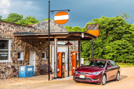 Colorful old style gas station with the car. Old style gas station with ancient pumps under the stormy skyline with refilling car.の写真素材