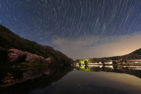 Cherry blossoms and stars reflected on the lake surfaceの写真素材