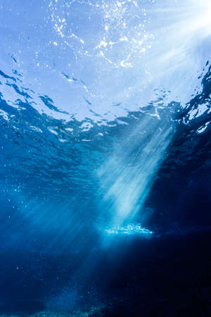 Rays of sunlight shining into sea, underwater viewの写真素材