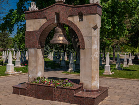 A large bronze bell under an arch in a Christian military cemetery.の写真素材