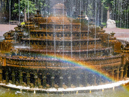 Old fountain in the city park. A beautiful rainbow in a cascade of jets of the fountain.の写真素材