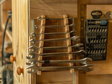 Carpenter's workshop. A set of wrenches and a set of screwdriver bits hang on a wooden wall.