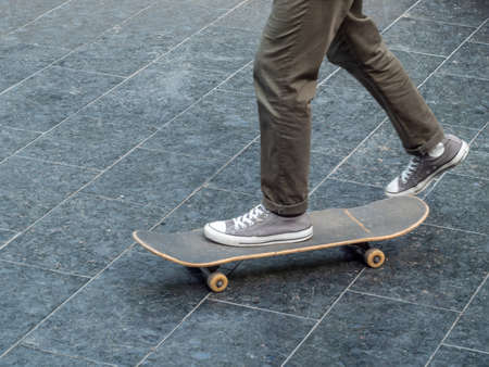 The teenager goes for a drive on a skateboard. The left foot is on the skateboard and the right foot is pushing off. Close-up.の写真素材