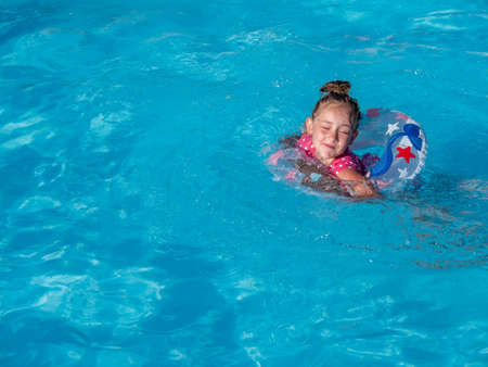 Happy little girl with colorful inflatable ring in swimming. Copy space.