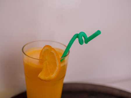 A glass of orange juice with an orange slice and a straw.の写真素材