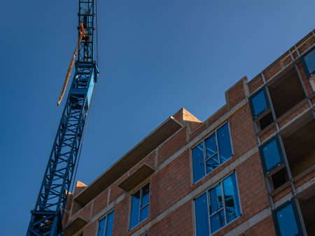 Construction crane against the background of a building under construction.